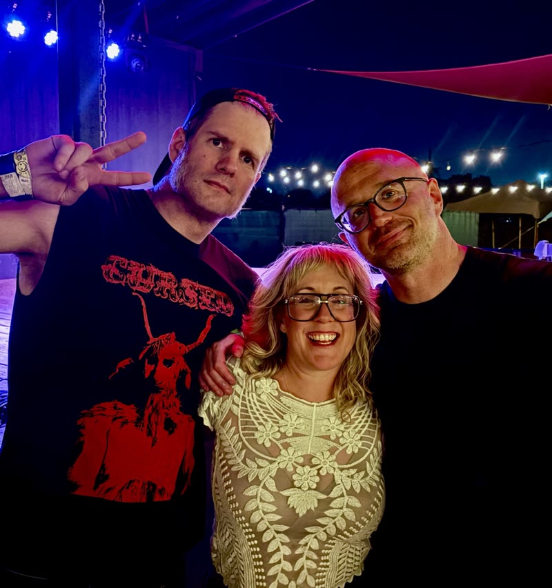 Dan and Tim posing with a friend under blue and red venue lights