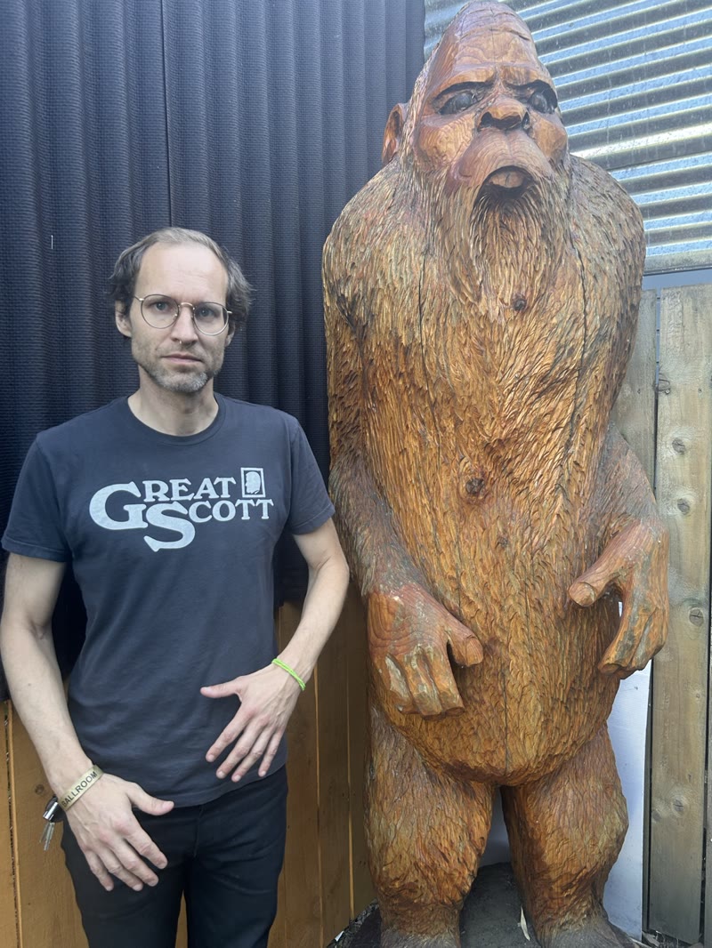 A member of the touring party standing beside a carved Bigfoot figure