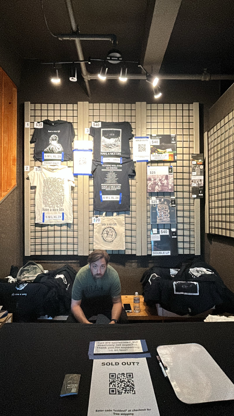 The Have A Nice Life merchandise table set up at a venue